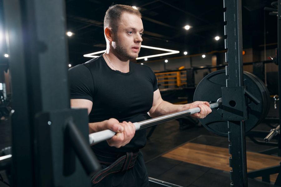 Młody sportowiec ćwiczy ze sztangą na siłowni