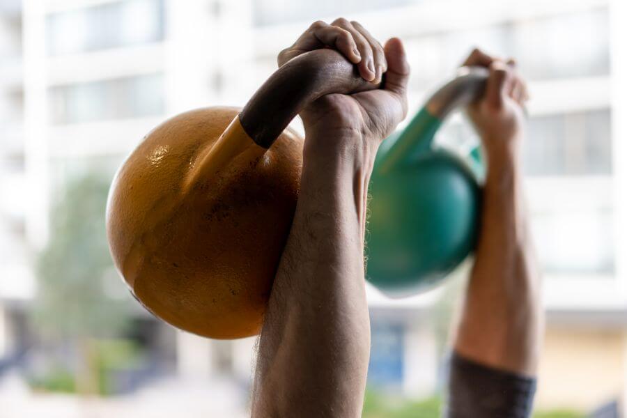 ręce trzymające kettlebells w górze