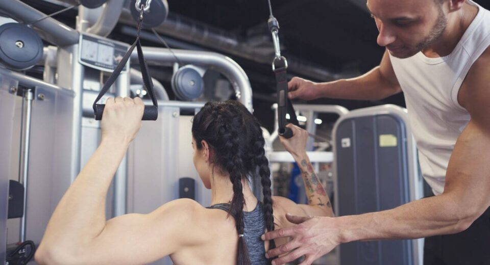 trener pokazuje dziewczynie ćwiczenia na atlasie